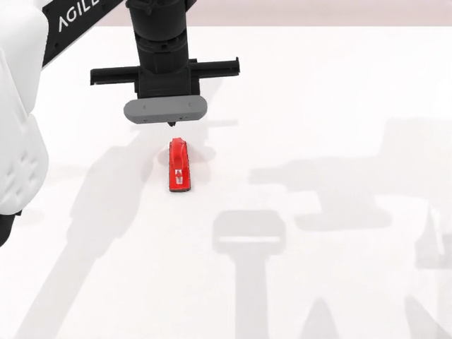 Robot gripper above a red tabletop object